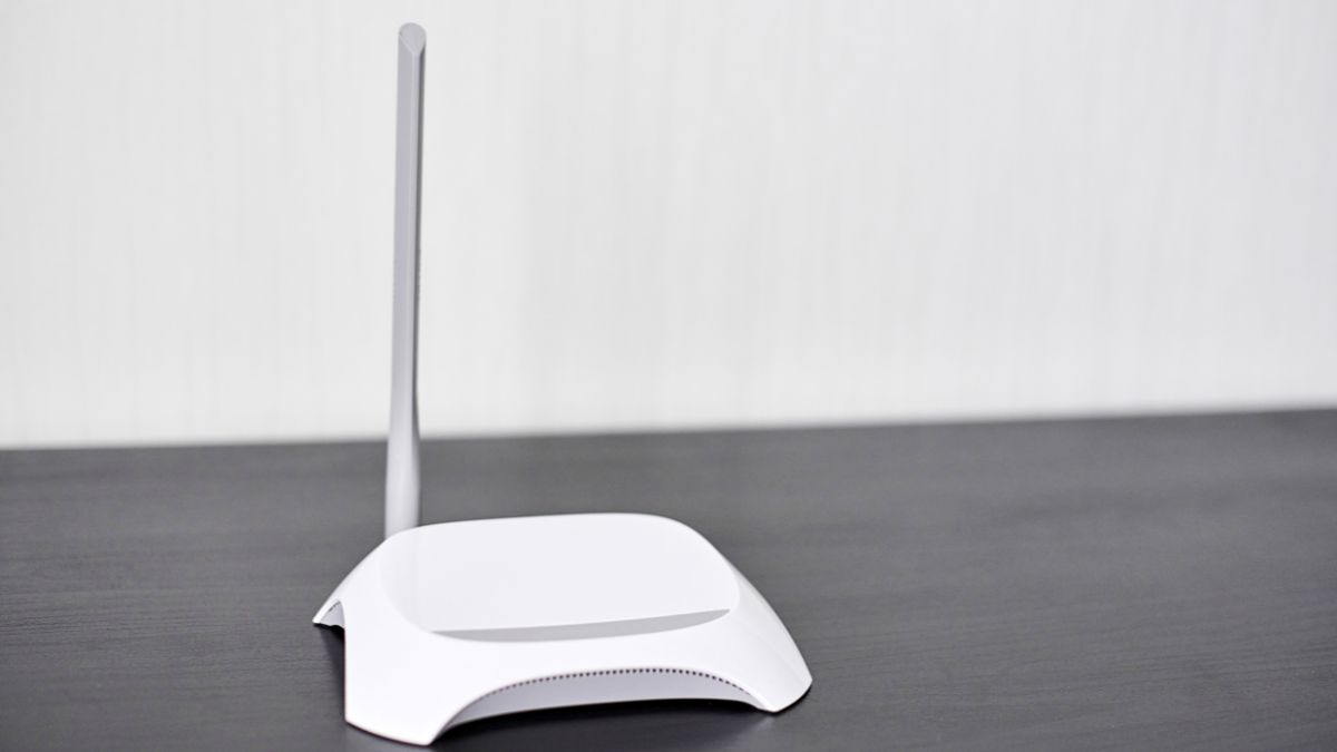 Biely router s anténou na čiernom stole, symbolizujúci internetové pripojenie.
