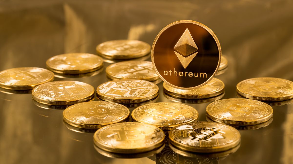 Zlaté mince Ethereum a Bitcoin rozložené na lesklom povrchu.