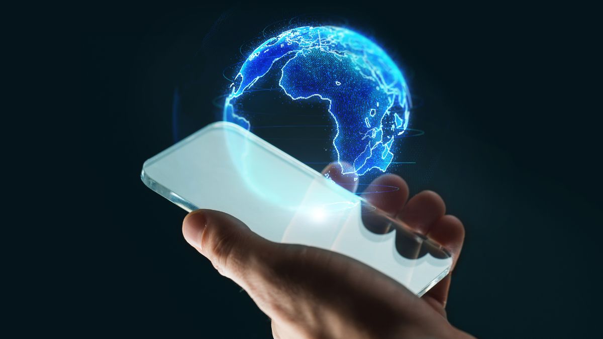 Ruka drží smartfón, z ktorého vychádza holografický 3D obraz Zeme.