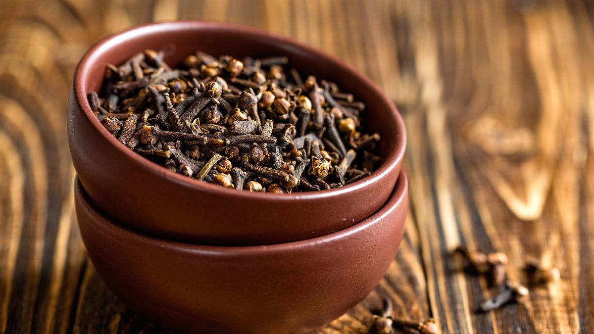 Dva hnedé keramické misky plné sušených klinčekov na drevenom stole.