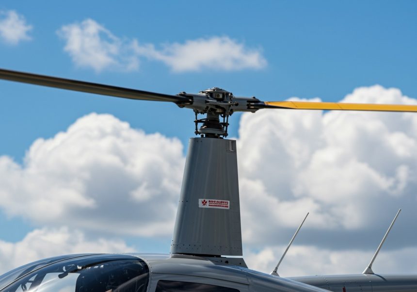 Detail rotora helikoptéry s modrou oblohou a bielymi oblakmi v pozadí.