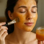 Žena s medovou pleťovou maskou na tvári a sklenenou nádobou s medom.