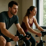 Dve osoby cvičia na stacionárnych bicykloch v domácom prostredí.
