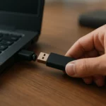 Osoba pripojuje USB k počítaču na drevenom stole
