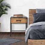 Dizajnový nočný stolík vedľa postele so zelenou rastlinou