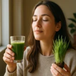 Žena vychutnáva jačmeňovú trávu v pohári a v ruke drží rastlinku.
