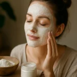Žena s maskou z bielej hliny na tvári a prírodními produktmi.