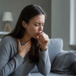 Žena trpiaca kašľom a ťažkosťami s dýchaním v interiéri.