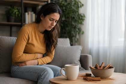 Žena so žalúdočnými ťažkosťami vedľa škorice a šálky čaju