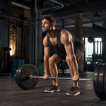 Muž zdvihajúci činku v modernom fitnes centre