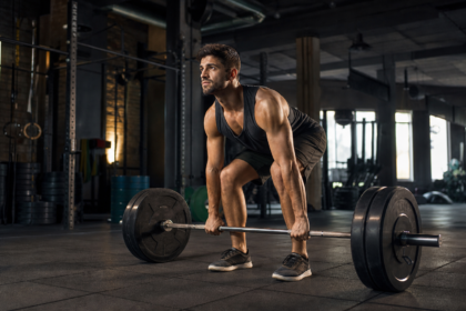 Muž zdvihajúci činku v modernom fitnes centre