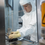 Pracovník v ochrannom obleku manipuluje s materiálom v laboratóriu s alfa žiarením.